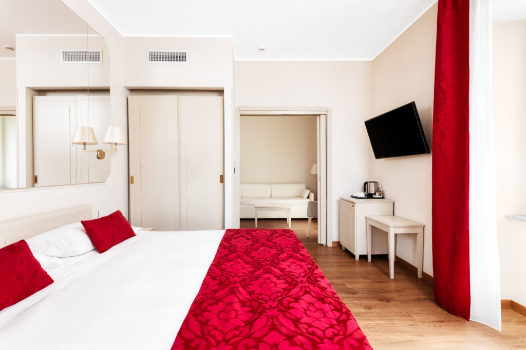 The image shows a double bedroom and another room with a sofa on the side.