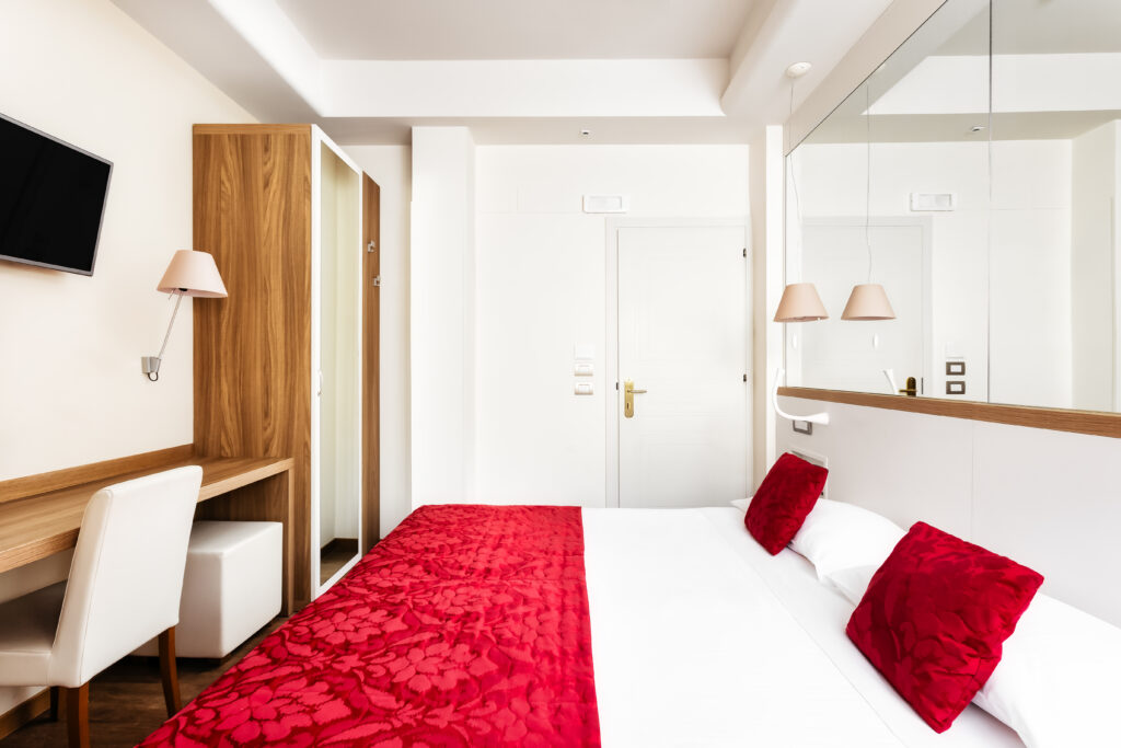 The image shows a double bedroom with a desk and wardrobe opposite.