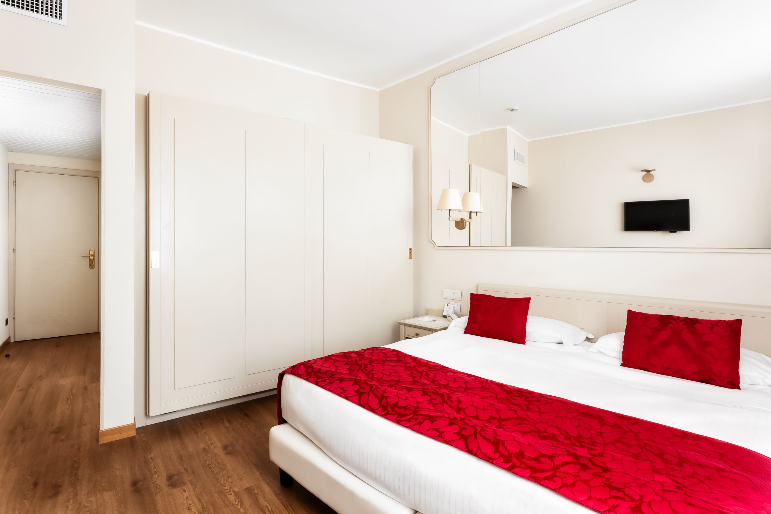 The image shows a double bedroom with a window and a tall wardrobe.