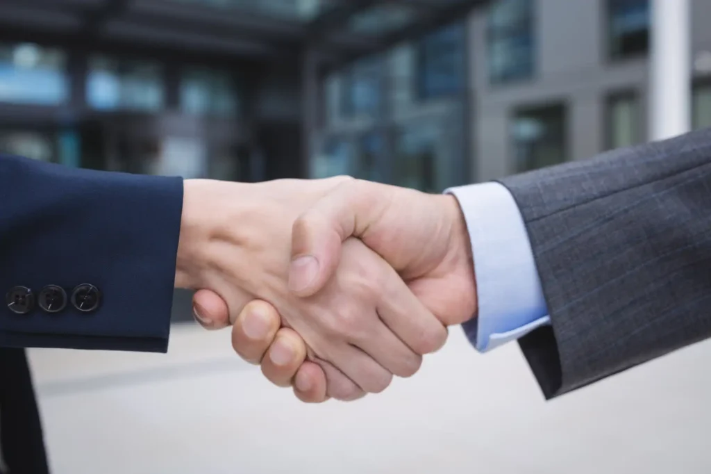 The image shows two people shaking hands.